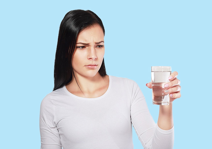 Woman looking at water wondering if chloramines and chlorines remain in her water